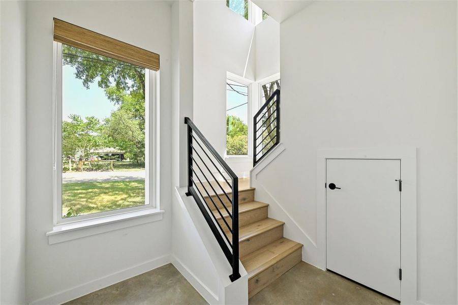 Clean-lined staircase with wood treads and black steel railing, flooded with natural light. Clean-lined staircase with wood treads and black steel railing, flooded with natural light.