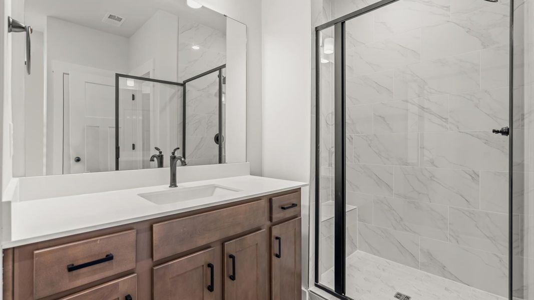 Highly functional and elegant en-suite with separate vanities, tiled walk-in shower, and refined finishes