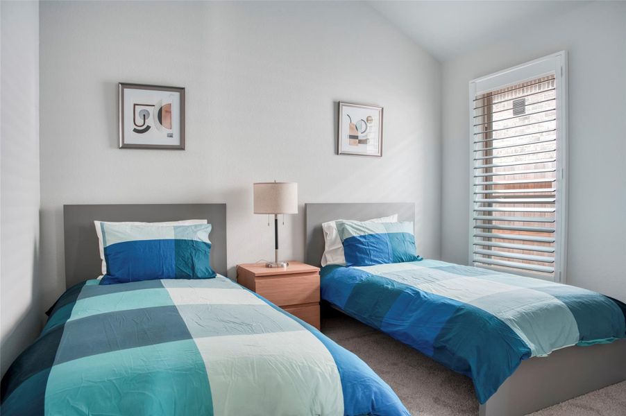 This cozy bedroom features two twin beds with modern blue bedding, a shared nightstand with a lamp, and a window with blinds, allowing natural light to brighten the space. Minimalist artwork decorates the walls, adding a contemporary touch. This cozy bedroom features two twin beds with modern blue bedding, a shared nightstand with a lamp, and a window with blinds, allowing natural light to brighten the space. Minimalist artwork decorates the walls, adding a contemporary touch.