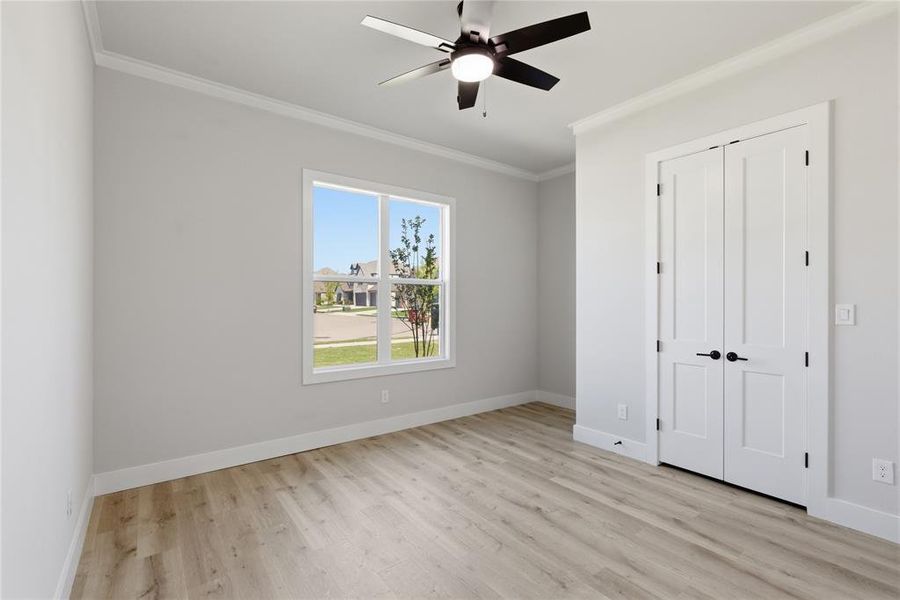 Bright room featuring wood-finish flooring, a contemporary ceiling fan, and a large window with white trim