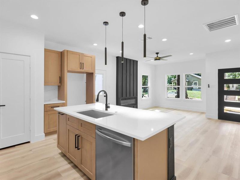 Kitchen featuring a center island with sink, dishwasher, ceiling fan, and light wood-type flooring