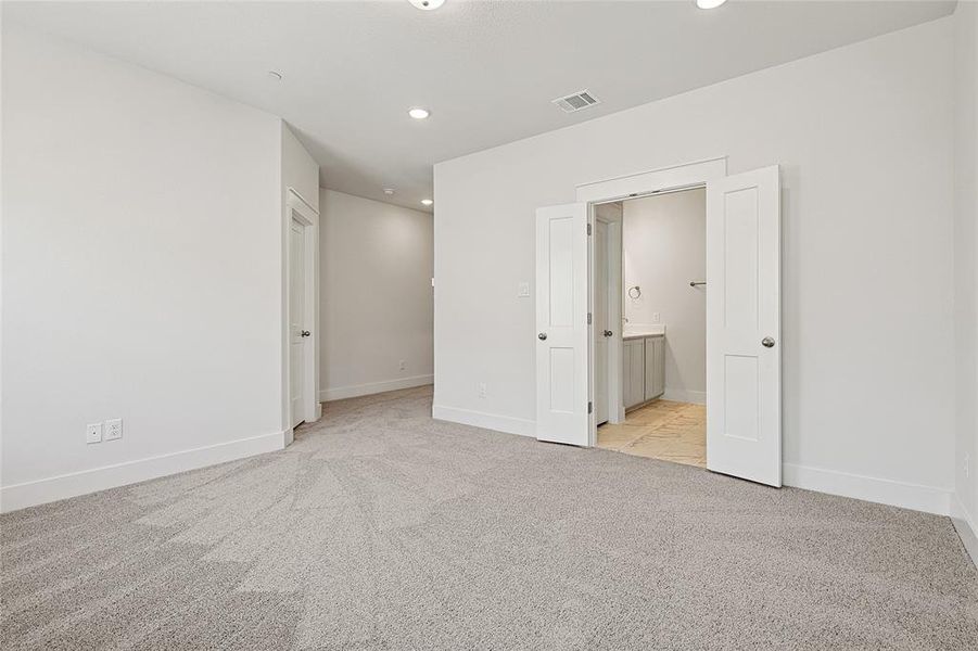 Walk-in closet featuring white shelving units, hanging rods, and carpeted flooring