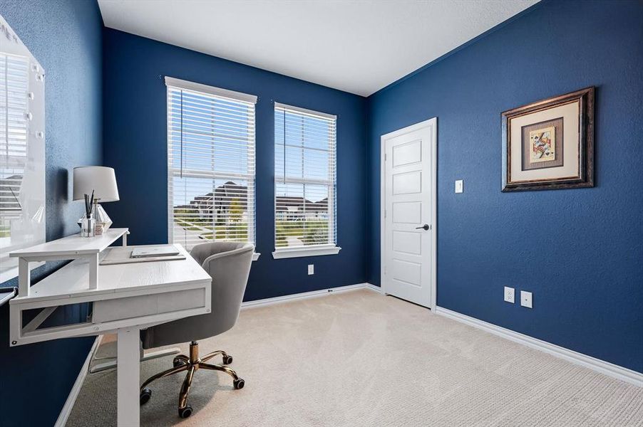 Carpeted office space with baseboards and a textured wall