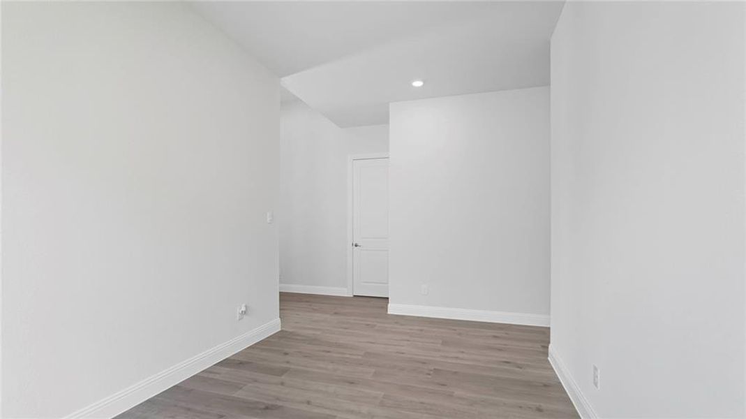Spacious room featuring light wood-finish flooring, white baseboards, and neutral wall tones