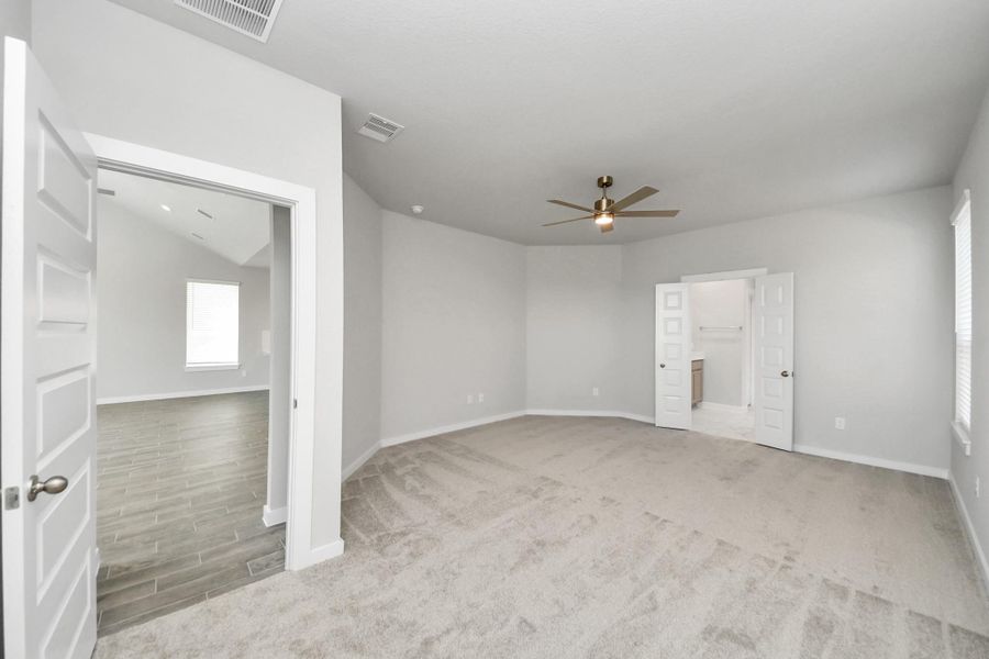 Escape and relax in the exquisite primary suite, a haven to unwind after a long day. The spacious room, located on first floor, boasts plush carpeting, soothing paint tones, high ceilings, and expansive windows adorned with privacy blinds. Sample photo of completed home with similar floor plan. Actual colors and selections may vary. Escape and relax in the exquisite primary suite, a haven to unwind after a long day. The spacious room, located on first floor, boasts plush carpeting, soothing paint tones, high ceilings, and expansive windows adorned with privacy blinds. Sample photo of completed home with similar floor plan. Actual colors and selections may vary.