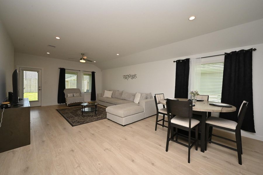 This spacious living and dining area features light wood flooring, large windows offering plenty of natural light, and a ceiling fan adds comfort. The space is open and inviting, perfect for relaxation and entertainment. This spacious living and dining area features light wood flooring, large windows offering plenty of natural light, and a ceiling fan adds comfort. The space is open and inviting, perfect for relaxation and entertainment.