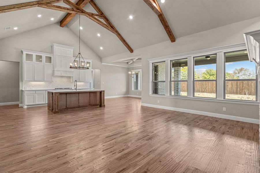Unfurnished living room with high vaulted ceiling, dark wood-style floors, beamed ceiling, a chandelier, and recessed lighting