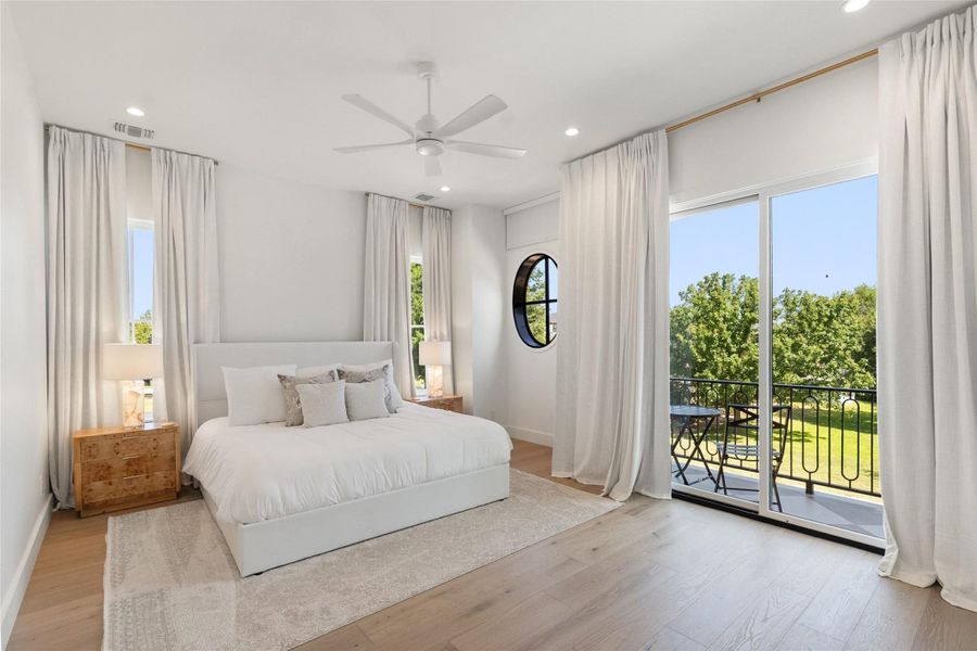A well-lit bedroom features hardwood floors, recessed lighting, and a private balcony overlooking a verdant landscape. A well-lit bedroom features hardwood floors, recessed lighting, and a private balcony overlooking a verdant landscape.