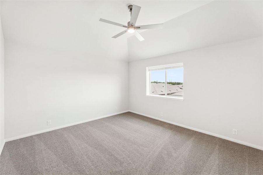 Empty bedroom with gray carpet, ceiling fan, vaulted ceiling, and single window