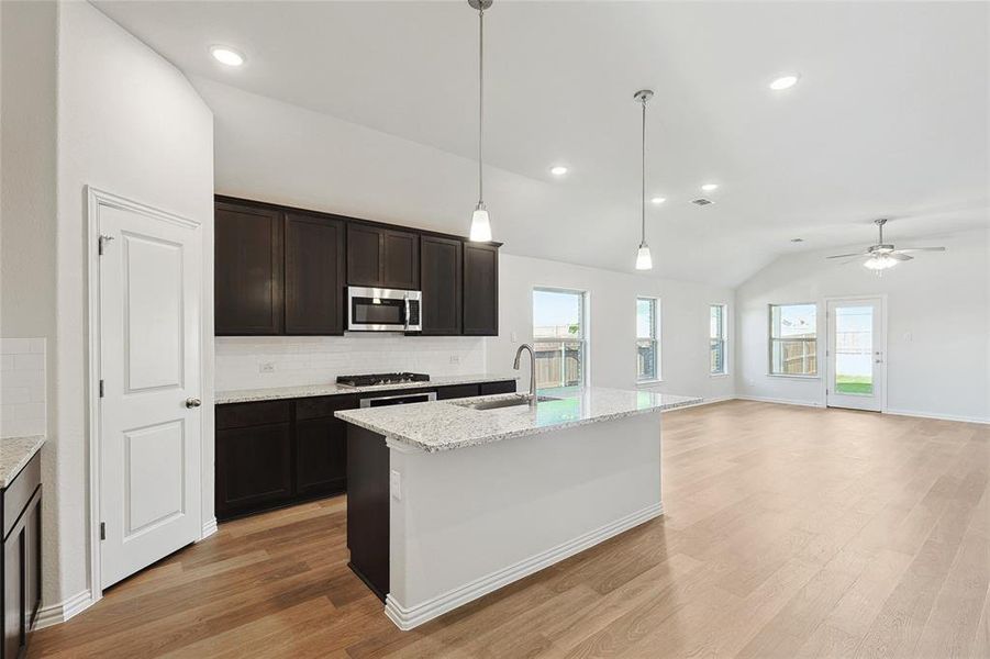 Kitchen featuring light hardwood / wood-style flooring, sink, decorative backsplash, a kitchen island with sink, and ceiling fan