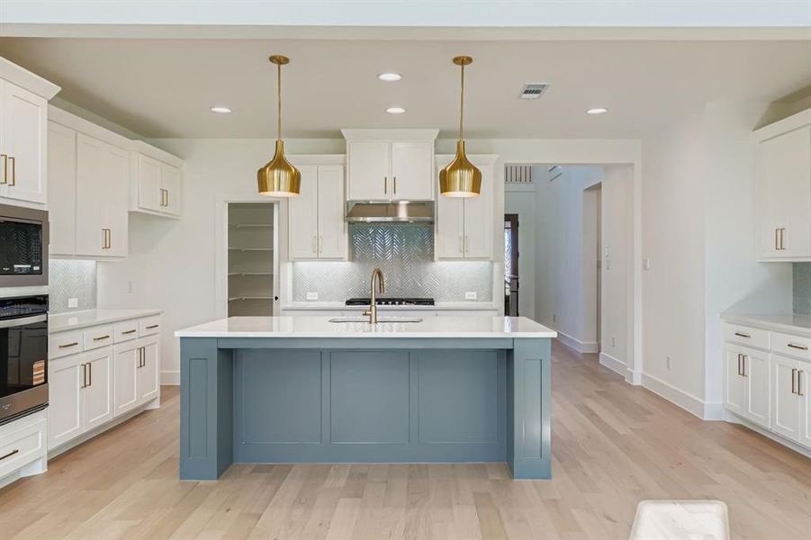 Kitchen featuring white cabinetry, backsplash, light stone counters, pendant lighting, and stainless steel appliances