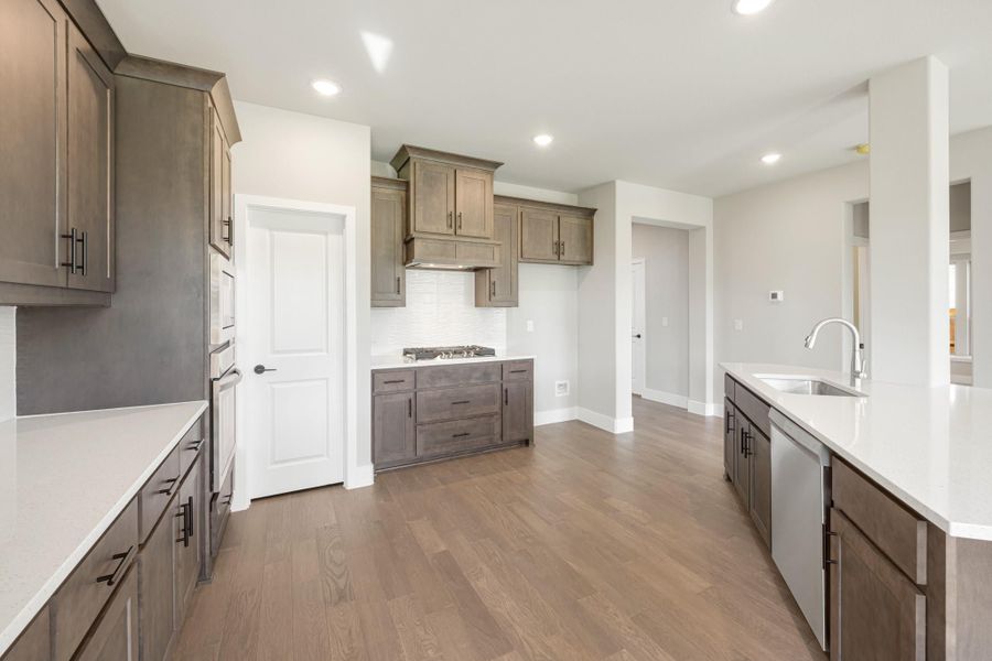 Kitchen with dark brown cabinets, white countertops, gas cooktop, and hardwood floors
