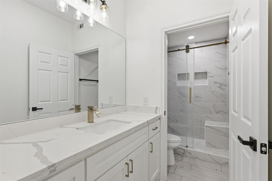 Downstairs bathroom featuring white vanity, large mirror, and frameless glass walk in shower.