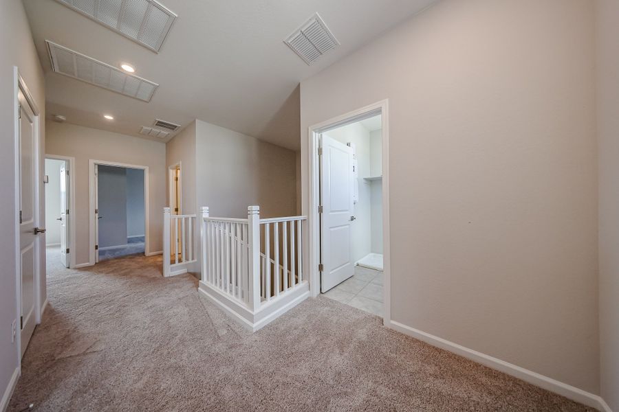 A hallway with a white railing.