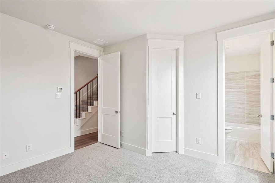 Unfurnished bedroom with ensuite bath and light colored carpet