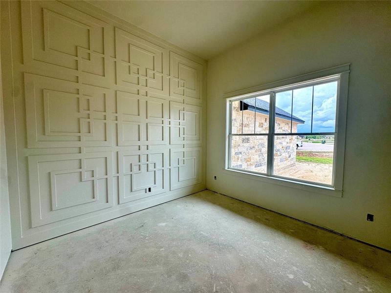An inviting room boasts a geometrically paneled accent wall and a large, naturally illuminated window.