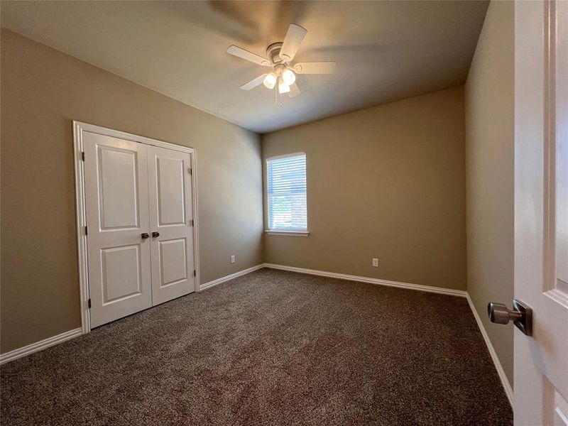 Unfurnished bedroom with a closet, dark colored carpet, and ceiling fan