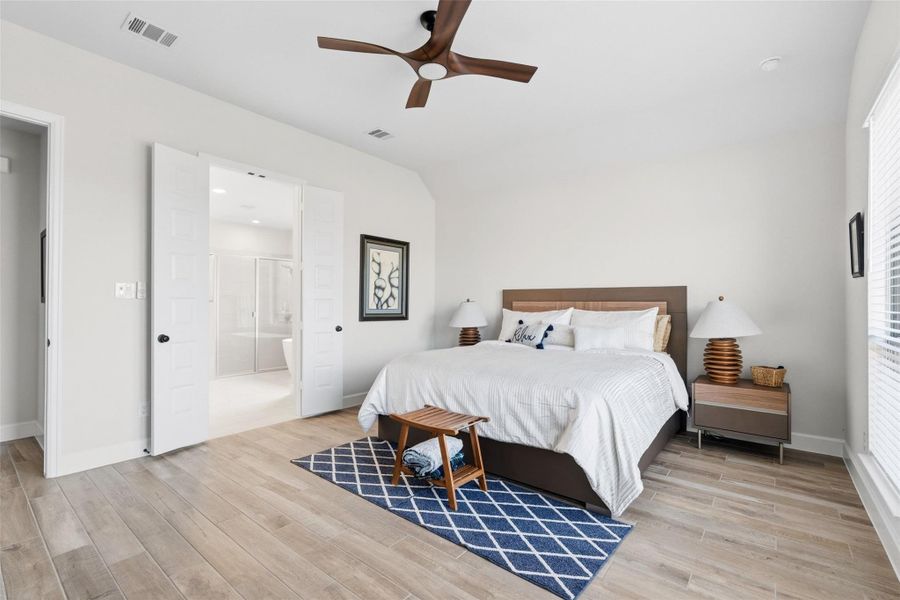 Spacious bedroom featuring wood-finish flooring, a contemporary ceiling fan, and white window blinds