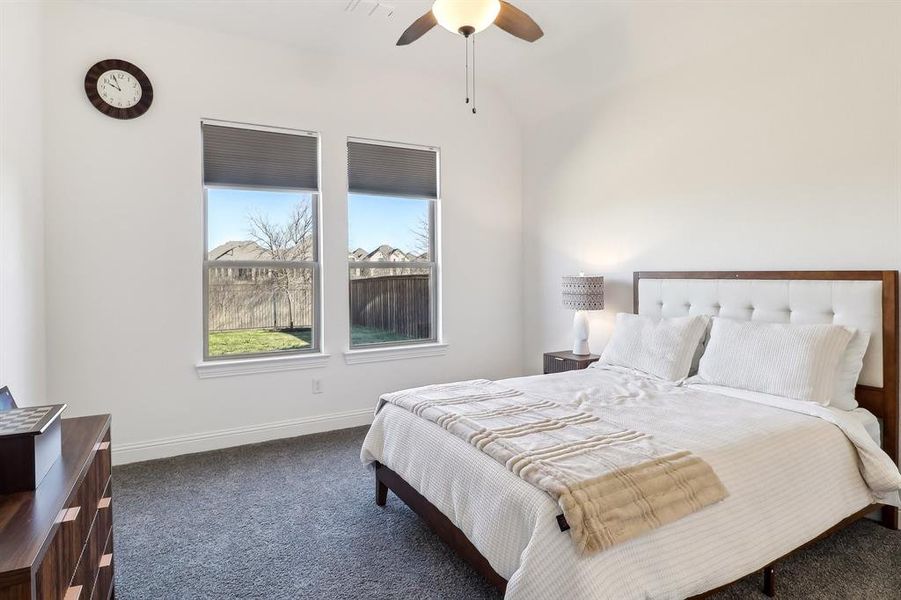 Carpeted bedroom featuring ceiling fan, vaulted ceiling, and baseboards Carpeted bedroom featuring ceiling fan, vaulted ceiling, and baseboards