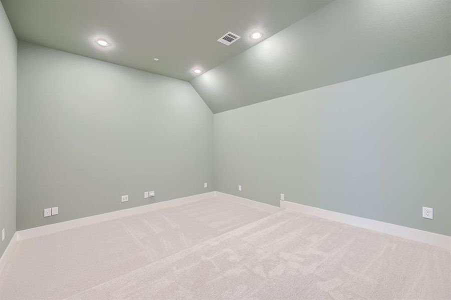 Carpeted empty room featuring vaulted ceiling