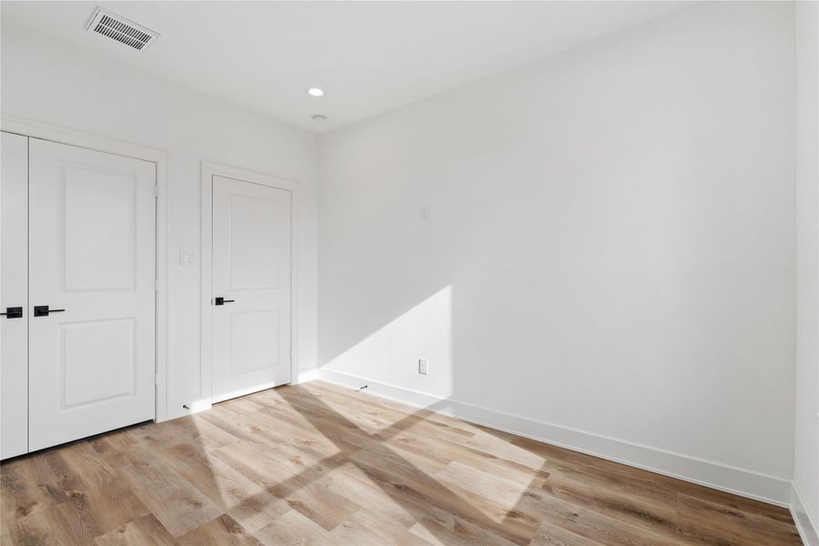 Bright secondary bedroom with modern flooring, clean lines, and a spacious closet.