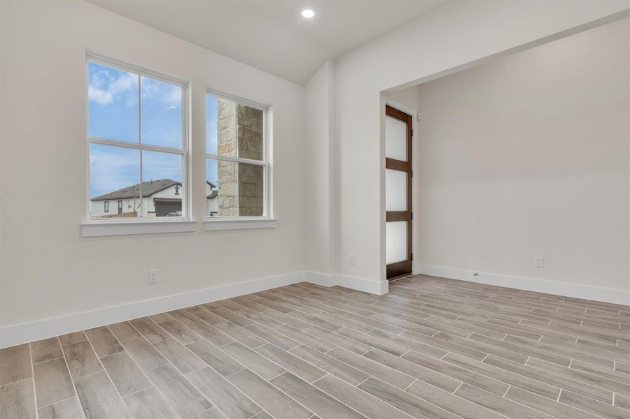 A versatile space features modern wood-look tile flooring and abundant natural light from multiple windows.