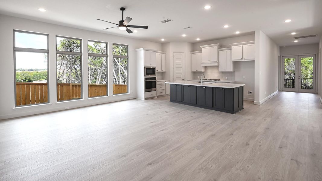 Kitchen with white cabinets, open floor plan, an island with sink, light wood-style flooring, and recessed lighting