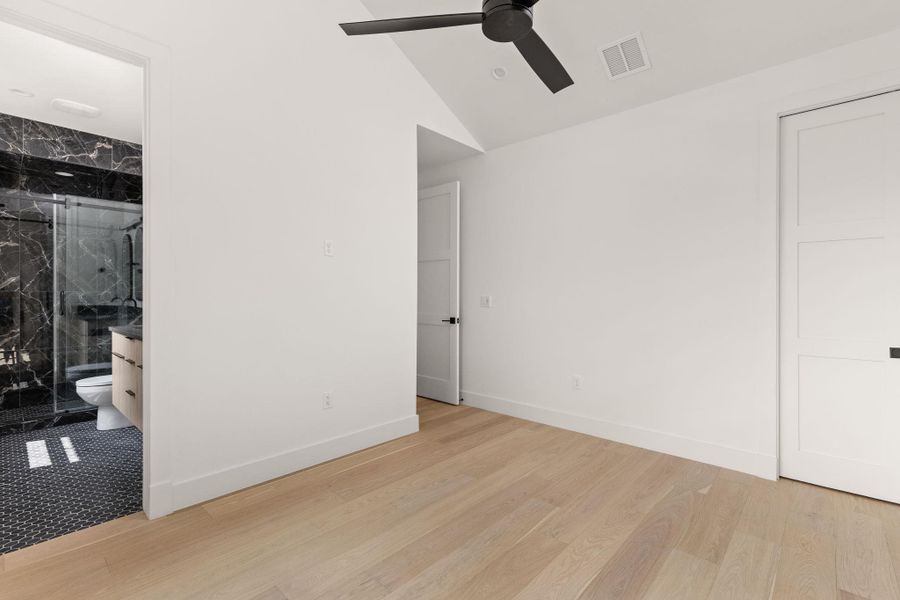 Unfurnished bedroom featuring ceiling fan, light wood-style flooring, ensuite bathroom, and vaulted ceiling Unfurnished bedroom featuring ceiling fan, light wood-style flooring, ensuite bathroom, and vaulted ceiling