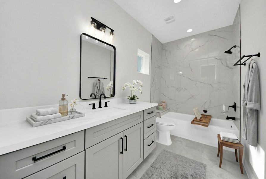 Stylish secondary bathroom featuring a quartz vanity, modern black fixtures, and a sleek tub-shower combo with marble-look tile surround.