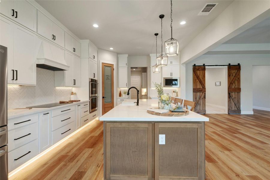Spacious kitchen featuring white cabinetry, a herringbone tile backsplash, and wood-finish flooring