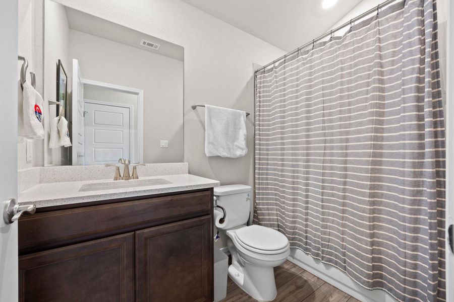 Full bath with dark wood-style flooring, vanity, and shower / tub combo with curtain Full bath with dark wood-style flooring, vanity, and shower / tub combo with curtain