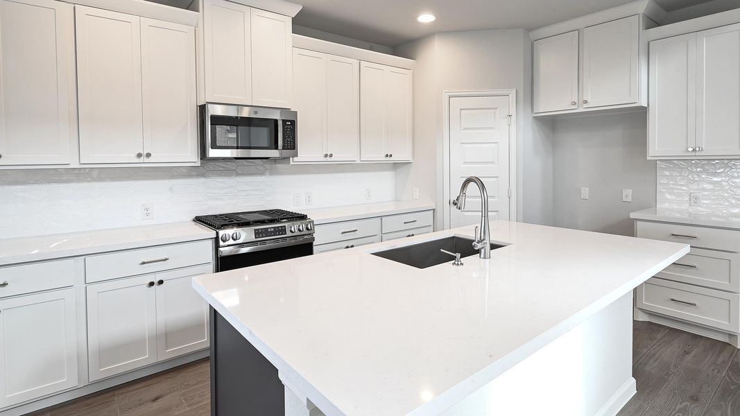 Kitchen featuring decorative backsplash, appliances with stainless steel finishes, light stone counters, white cabinetry, and recessed lighting Kitchen featuring decorative backsplash, appliances with stainless steel finishes, light stone counters, white cabinetry, and recessed lighting