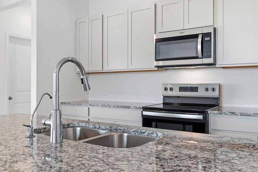 Kitchen featuring granite countertops, stainless steel appliances, a double basin sink with a gooseneck faucet, light cabinetry, and an electric range Kitchen featuring granite countertops, stainless steel appliances, a double basin sink with a gooseneck faucet, light cabinetry, and an electric range