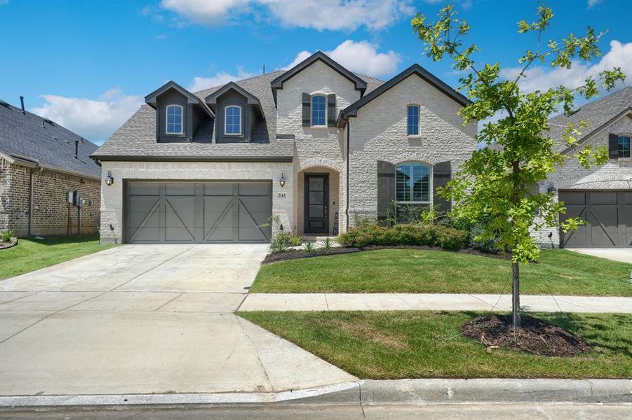 French country inspired facade featuring a front lawn and a garage