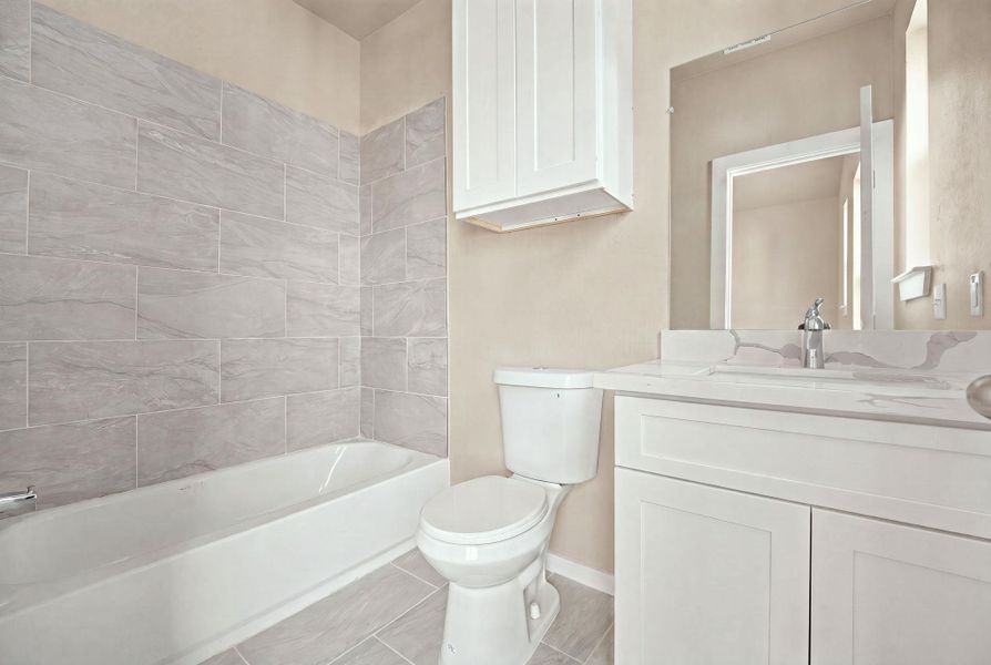 Modern stone tile surrounds the soaking tub in this cleanly detailed bathroom space.