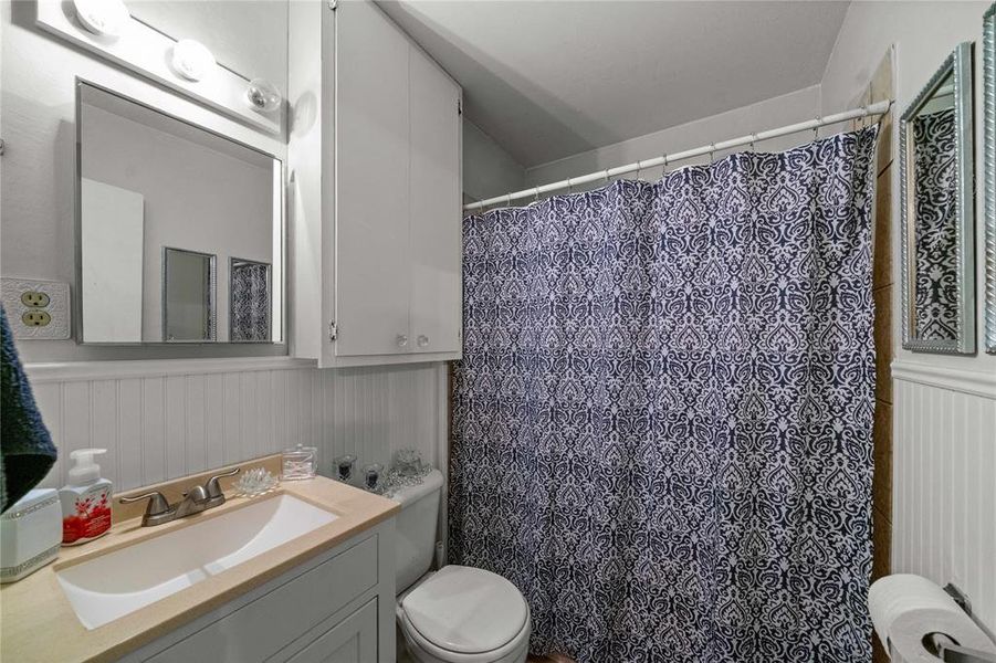 Bathroom with vanity, a shower with curtain, and wainscoting
