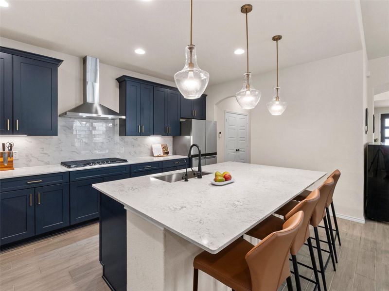 Kitchen with a kitchen bar, tile floors, blue cabinetry, and a center island with sink