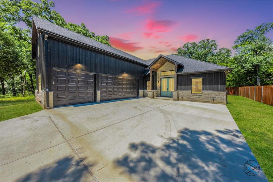 View of front of property featuring a shingled roof, driveway, a garage, and board and batten siding