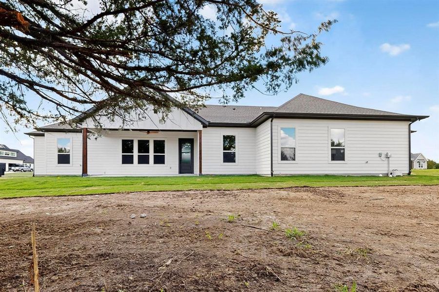 Rear view of house with a lawn and roof with shingles
