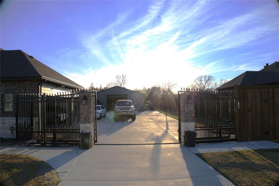 New Addition - Gate at dusk with a fenced front yard, an outdoor structure, and a driveway area