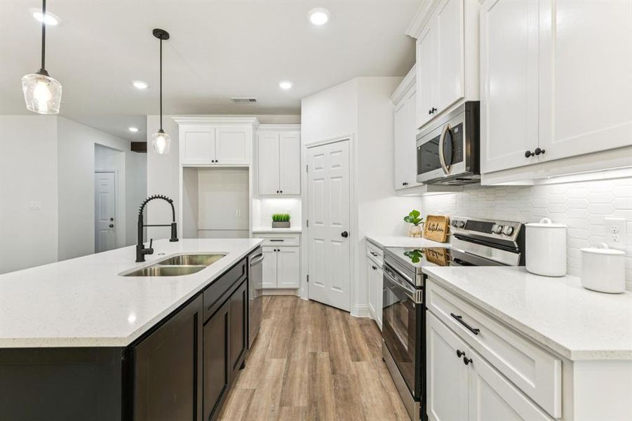 Kitchen with appliances with stainless steel finishes, a center island with sink, white cabinets, light stone countertops, and recessed lighting