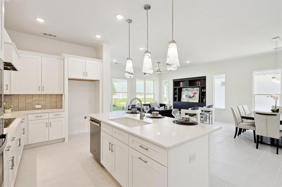 Kitchen featuring an island with sink, backsplash, light tile floors, hanging light fixtures, and sink