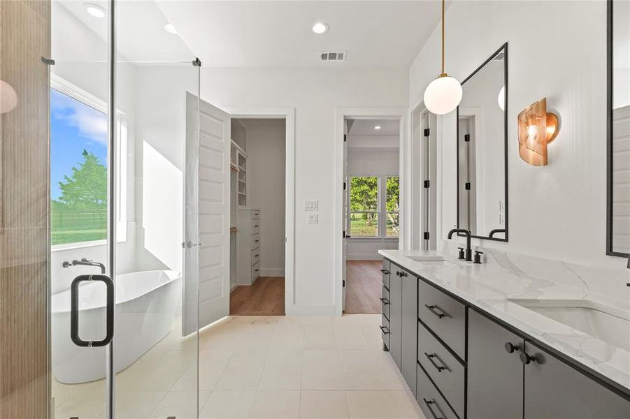 Bathroom featuring a freestanding bath, double vanity, recessed lighting, light tile patterned flooring, and a stall shower Bathroom featuring a freestanding bath, double vanity, recessed lighting, light tile patterned flooring, and a stall shower
