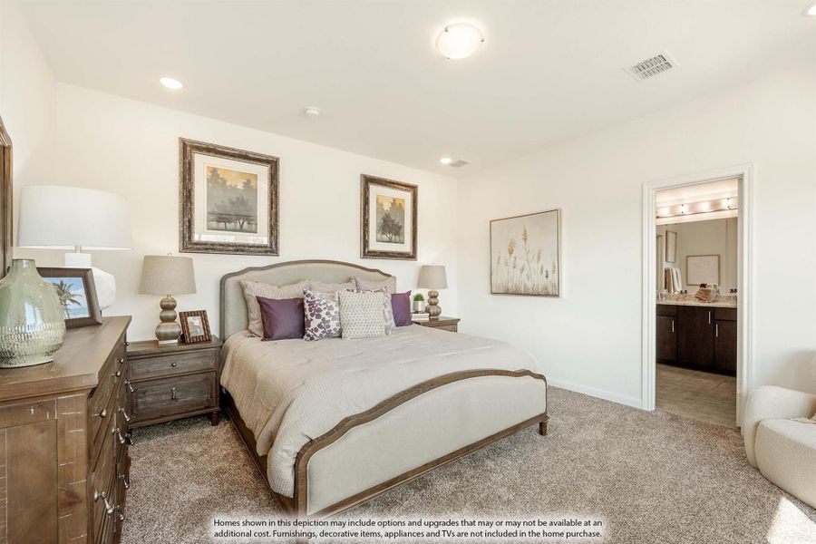 Master bedroom with upholstered bed, wood dresser, carpet flooring, and ensuite bathroom visible through doorway