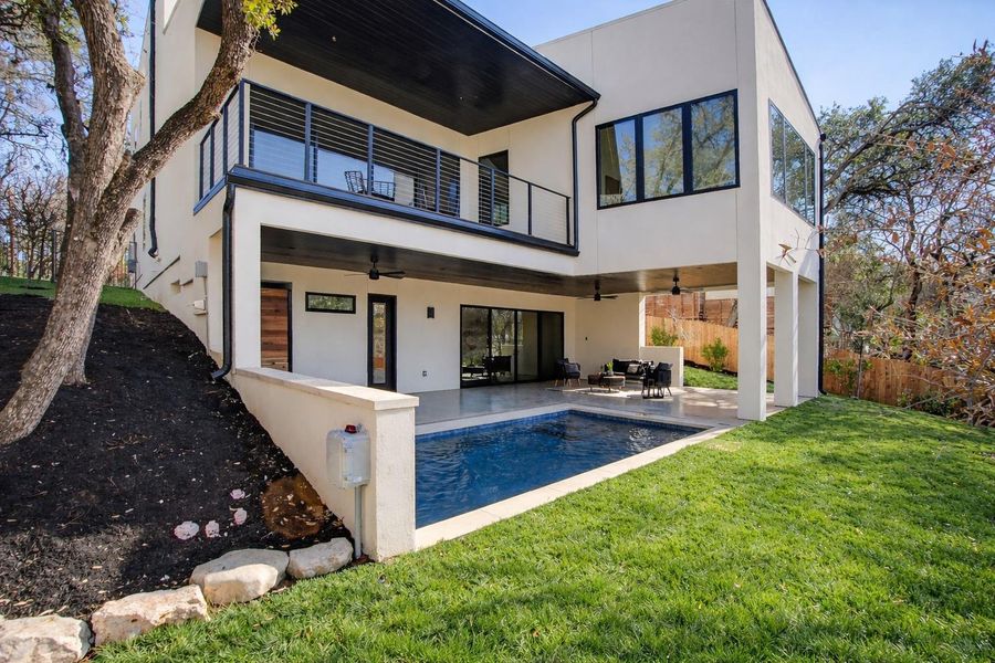 Back of house featuring ceiling fan, stucco siding, a patio area, an outdoor pool, and a balcony