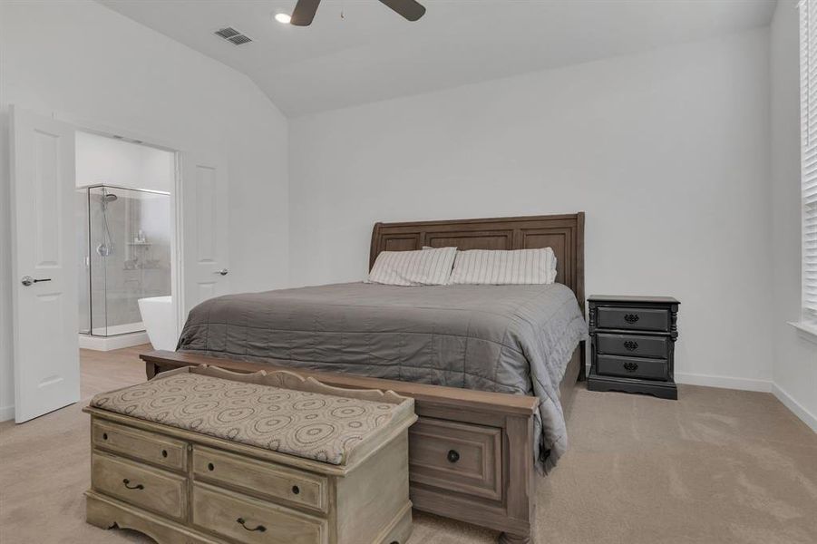 Bedroom featuring light colored carpet, lofted ceiling, a ceiling fan, and ensuite bath