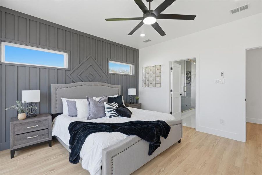 Bedroom with an accent wall, light wood-style floors, recessed lighting, ceiling fan, and connected bathroom