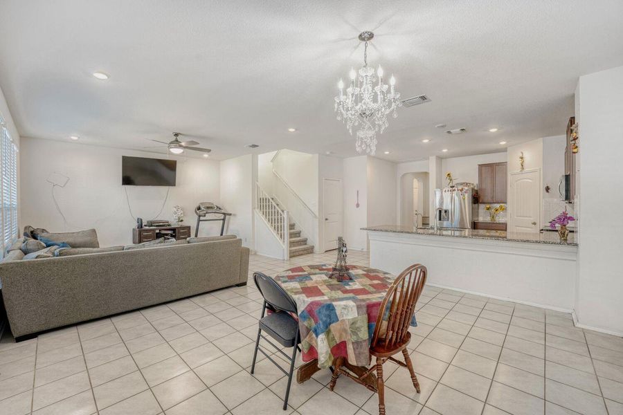 Dining space featuring stairs, a ceiling fan, light tile patterned floors, recessed lighting, and a chandelier