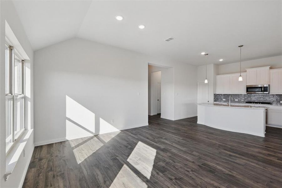Unfurnished living room featuring dark wood-style floors, vaulted ceiling, and recessed lighting