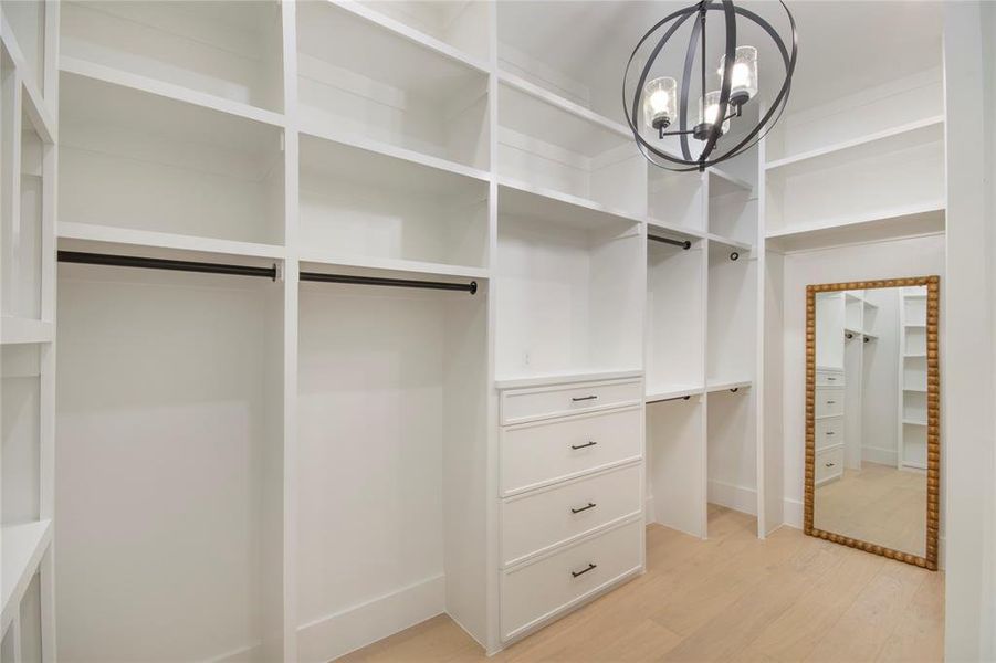 Spacious closet featuring light wood-style floors and a chandelier Spacious closet featuring light wood-style floors and a chandelier